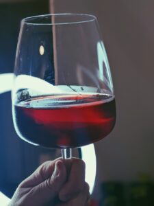 A wine glass with blackcurrant cider being held up to the light.