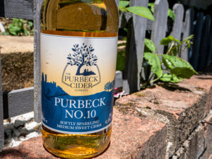 Purbeck No.10 Cider sitting a brick wall of a garden.
