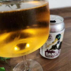 Dandy Dab cider in a wine glass with the 330ml can in the background.